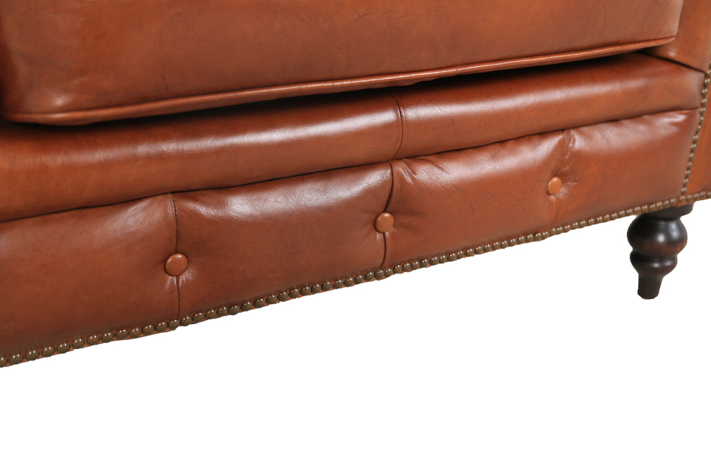Close-up of the Arthur arm chair's button-tufted front and turned leg