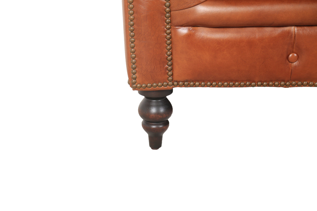 Close-up of the Arthur sofa's turned leg, nailhead trim and cognac leather
