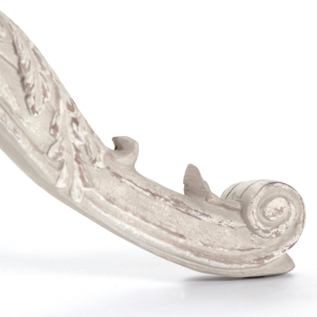 Close-up of the Chandler table's carved scroll foot in a cream finish