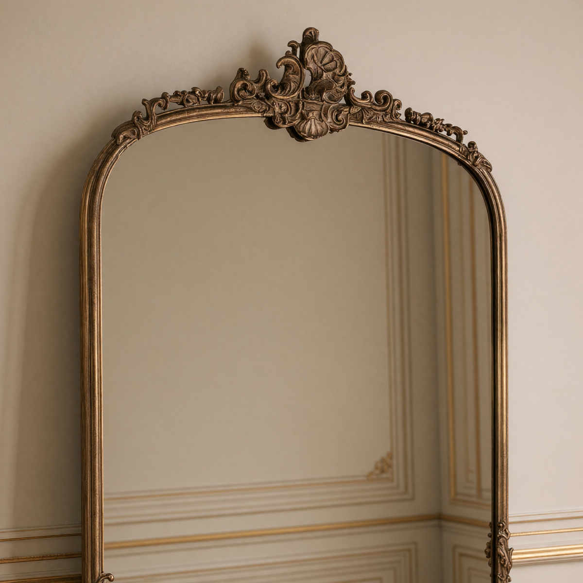 Close view of the ornate crest and arched top of the Godric French gilded metal arch floor mirror