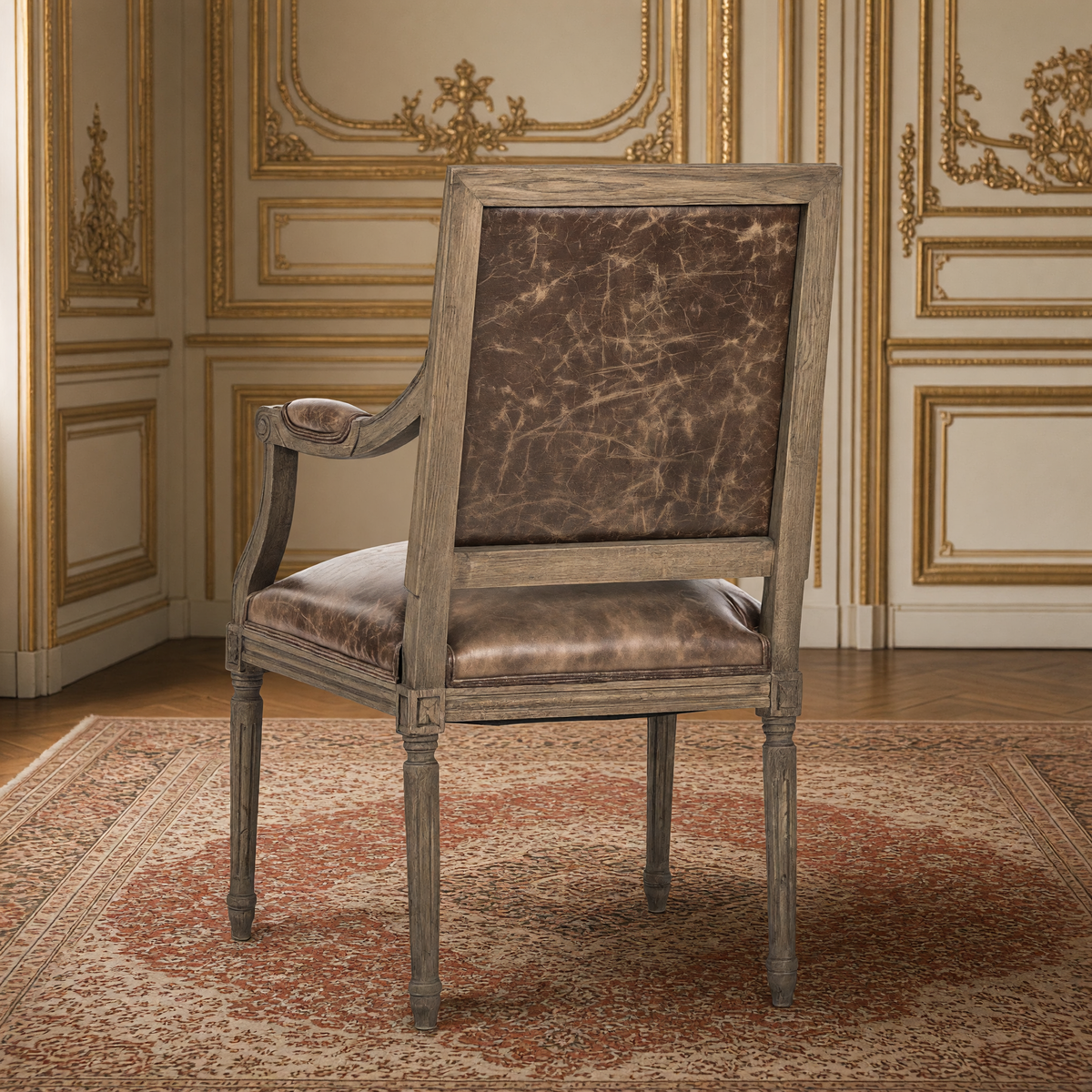 Back view of the Louis French carved oak square-back arm chair in Brown Leather, natural oak, in the same gilded salon