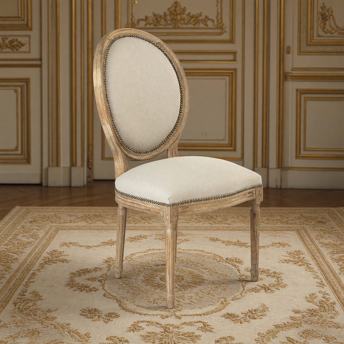 Medallion French oval-back side chair in natural linen with nailhead, limed grey oak in a gilded Louis XVI salon on an Aubusson carpet