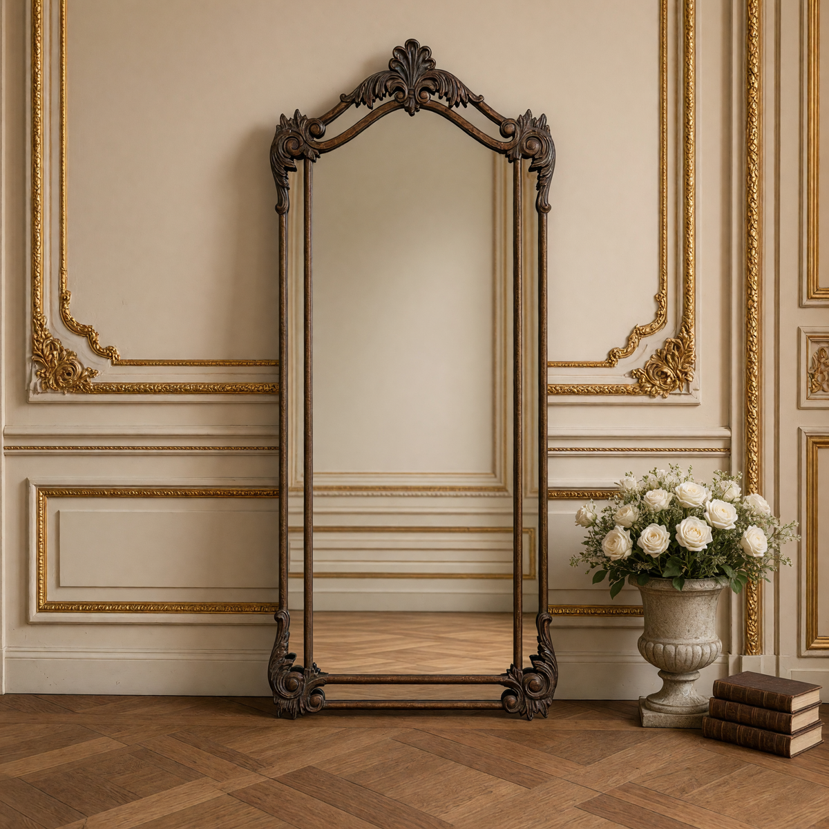 Aurelia floor mirror in antiqued bronze-brown with a stone urn of white roses and leather books beside it