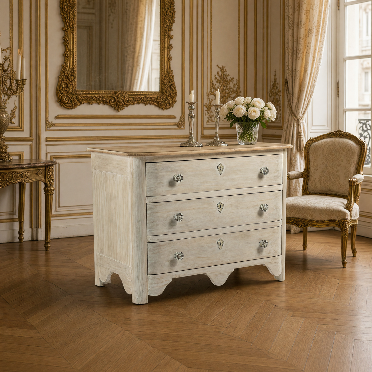 Patric French Painted Elm Chest in Whitewash with Natural Top styled beneath a gilded mirror with candlesticks, white roses and a Louis XVI bergere