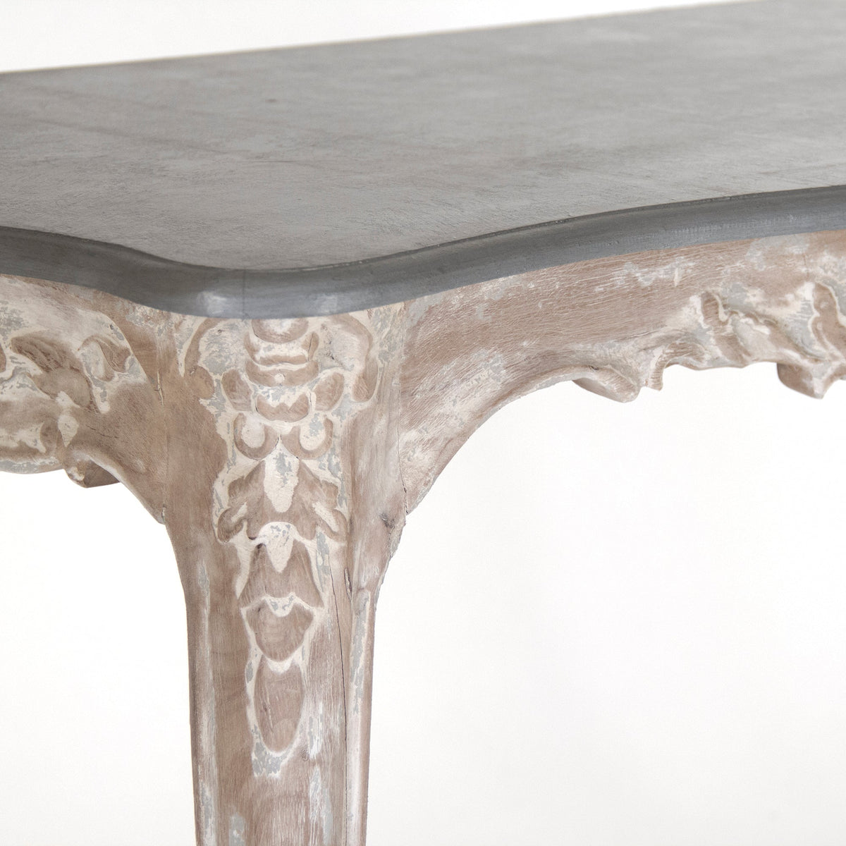 Close-up of the Reuben console's slate grey top and carved limed white leg